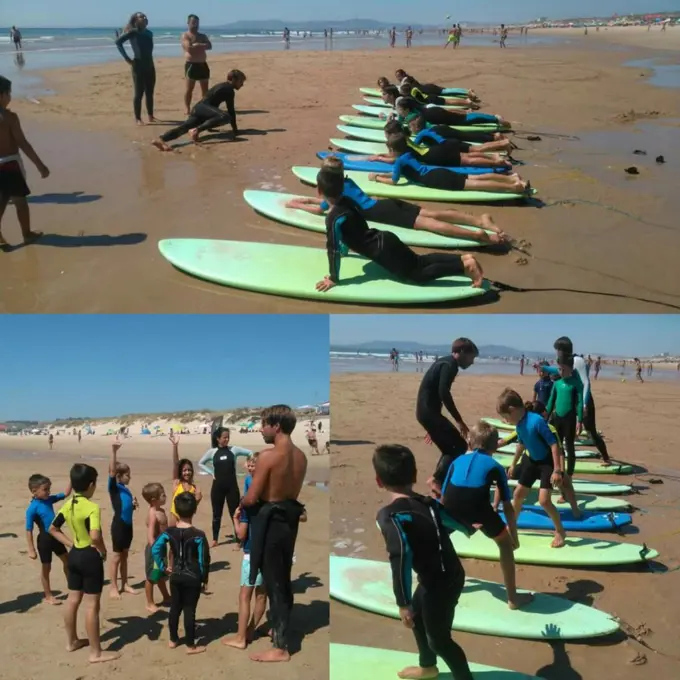 Crianças a treinar o take-off em pranchas soft e a reunir-se com os treinadores numa aula de grupo na praia