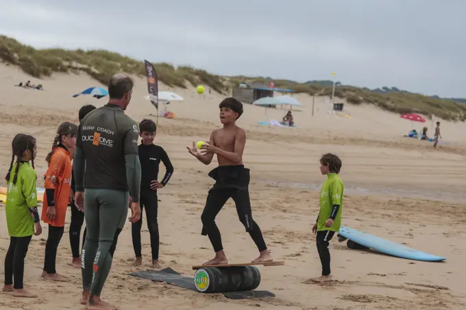 Treinador da Duck Dive com um grupo de crianças a treinar equilíbrio na areia